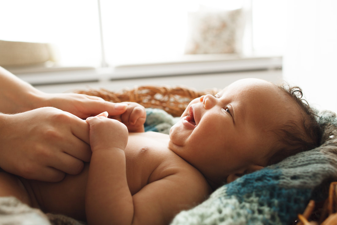 Bébé calme allongé sur le ventre, regardant attentivement l'objectif, sur un fond blanc épuré - représentation parfaite de l'environnement sain et apaisant offert par GraineSante pour la petite enfance dans les Pyrénées-Orientales.